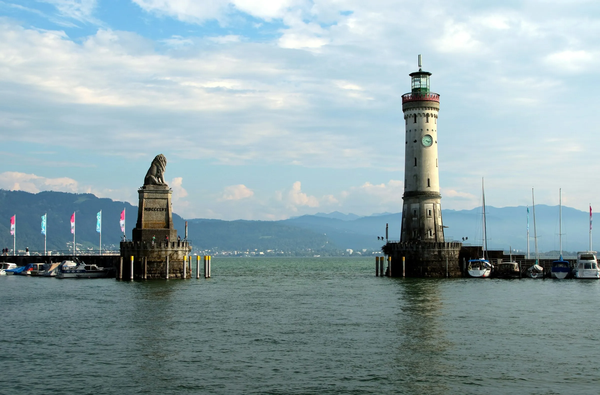Hafeneinfahrt von Lindau mit dem Bayerischen Löwen auf seinem Sockel und dem Neuen Leuchtturm, dahinter Berge