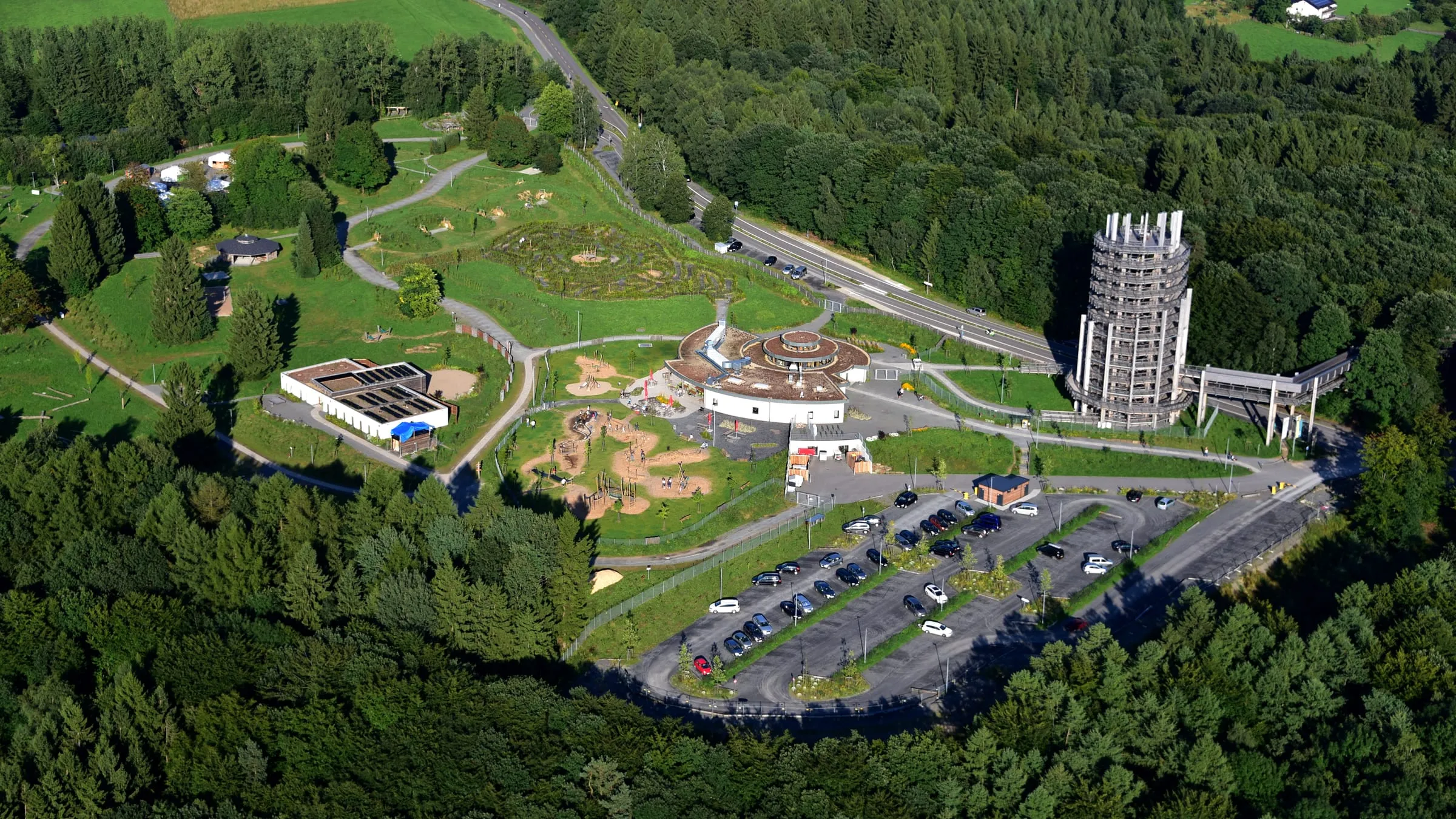 Luftbild des Waldparks Panarbora bei Waldbröl mit hölzernem Aussichtsturm, Spielflächen und umgebendem Nadelwald