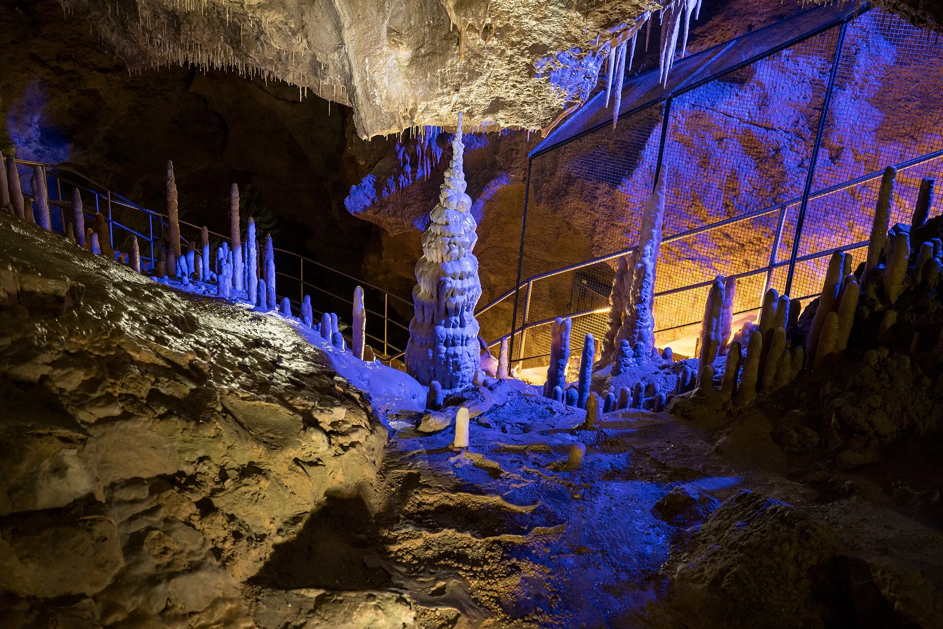 Beleuchtete Tropfsteine und ein Besuchersteg mit Geländer in der Teufelshöhle bei Pottenstein