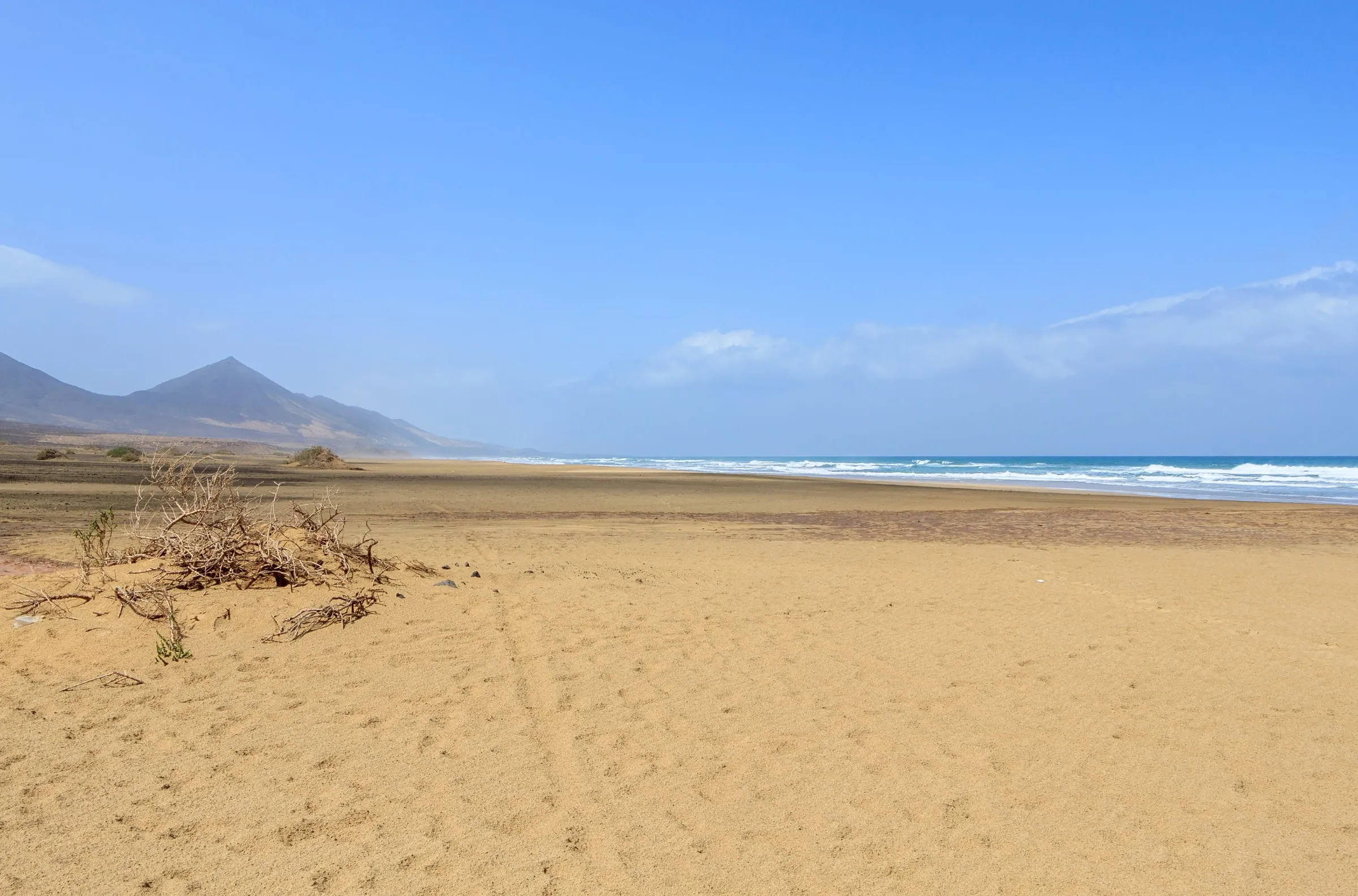Leerer Sandstrand von Cofete, links die kahlen Berge des Jandía-Massivs, rechts die Brandung des offenen Atlantiks