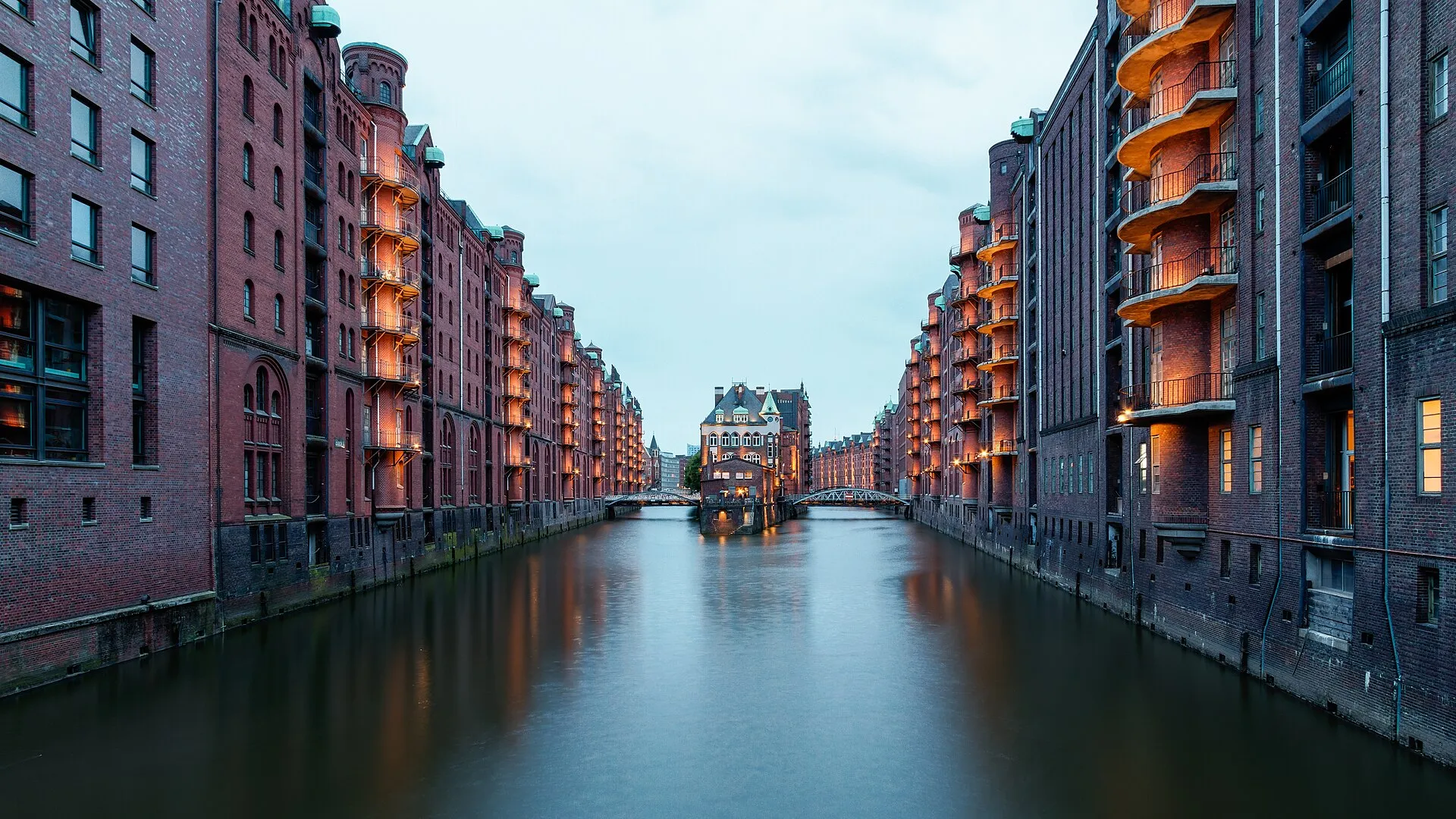 Wasserschloss in der Hamburger Speicherstadt in der Abenddämmerung, beleuchtete Backsteinspeicher links und rechts des Fleets